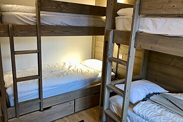 A bunk bed with white sheets and a ladder