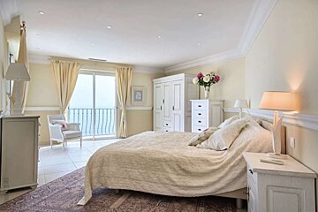 A bedroom with a large bed and a balcony
