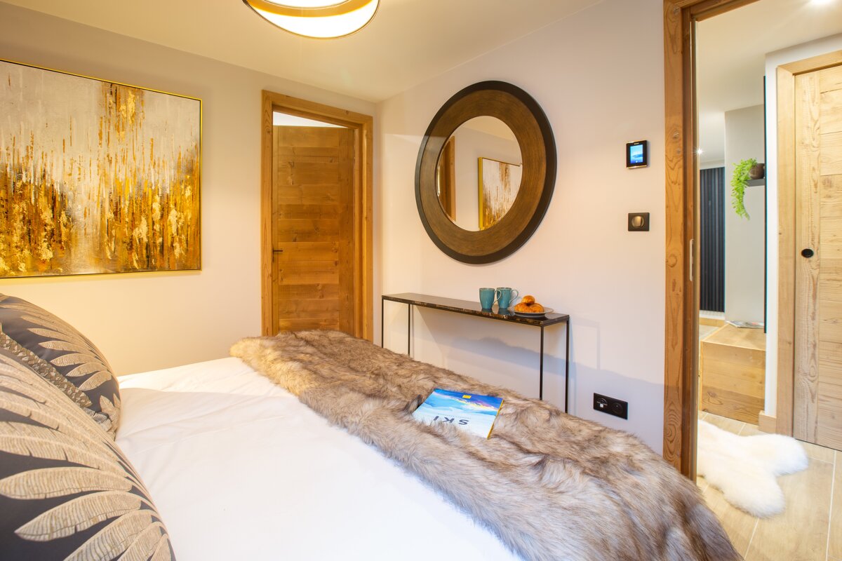 A bedroom with a painting on the wall and a mirror