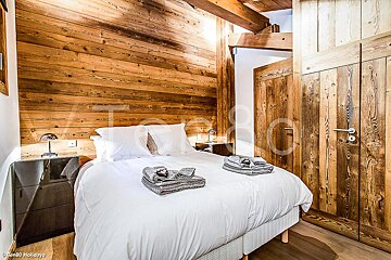 A bedroom with wood paneling and a bed with white sheets