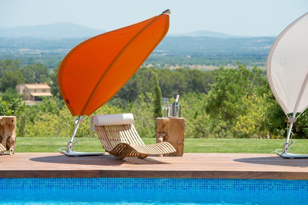 A swimming pool with a chair under an orange umbrella