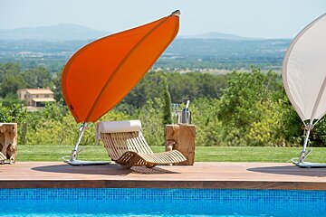 A swimming pool with a chair under an orange umbrella