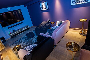 A living room with purple walls and a pink couch