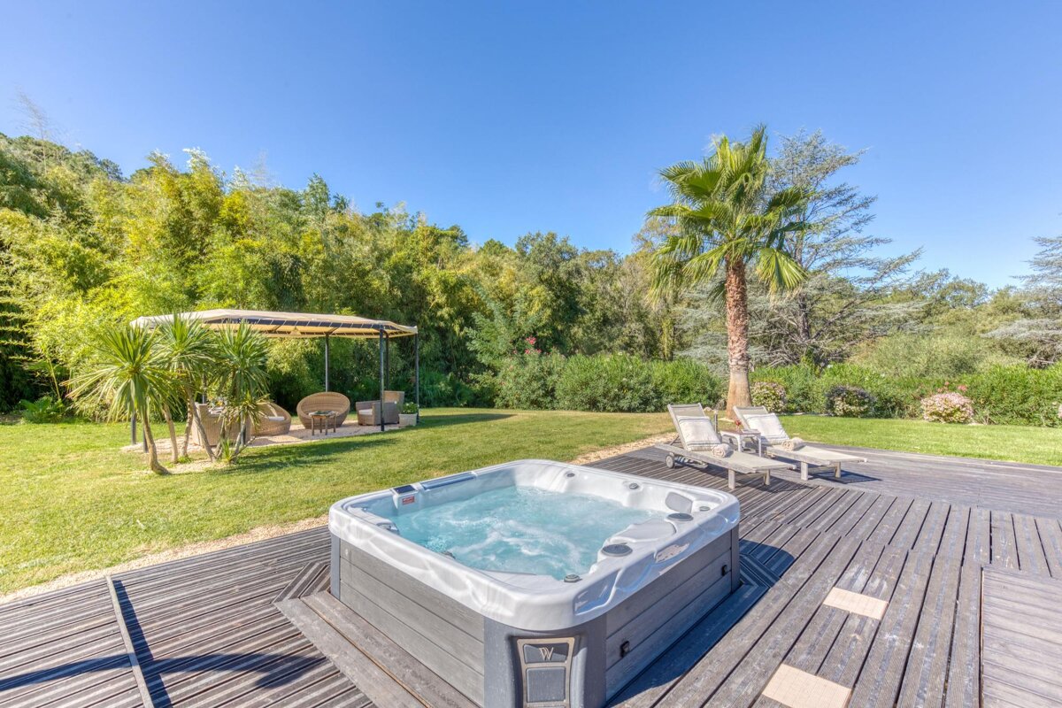 A hot tub sits on a wooden deck next to a gazebo