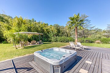 A hot tub sits on a wooden deck next to a gazebo