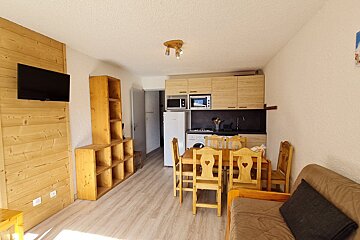 A living room with a table and chairs and a flat screen tv