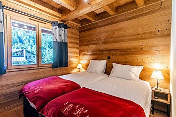 A wooden bedroom with two beds and a window