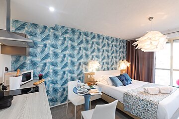 A bedroom with a bed and a table with a magazine on it