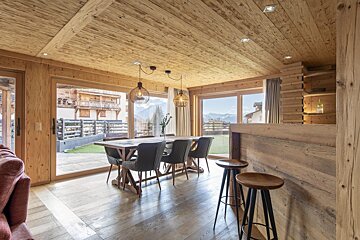 A wooden dining room with a table and chairs
