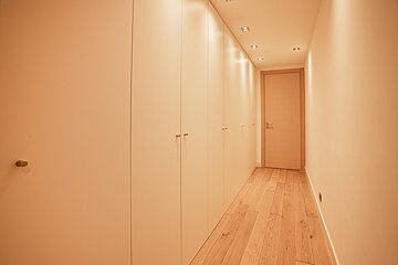 A hallway with wooden floors and white cabinets