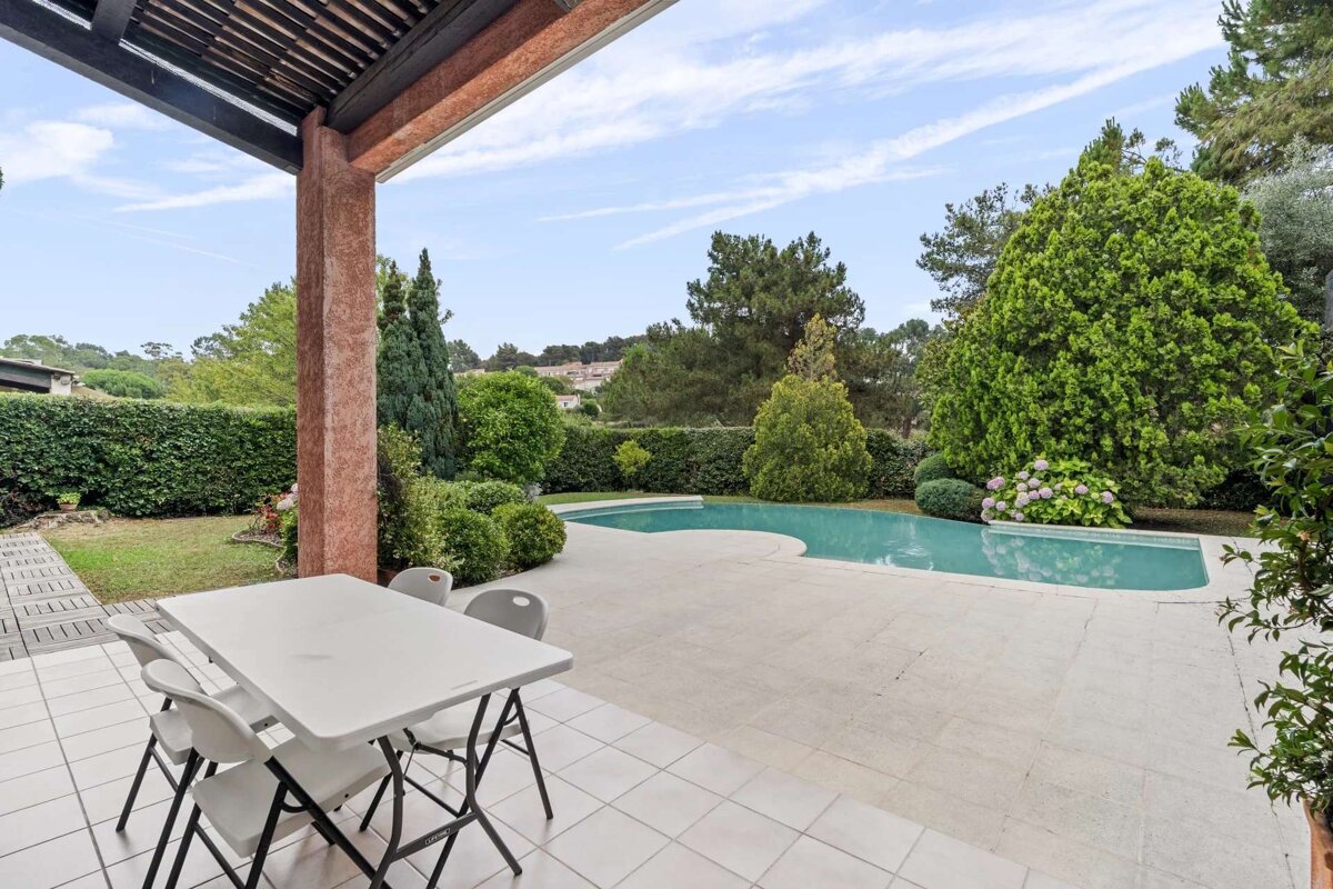 A patio with a table and chairs and a swimming pool