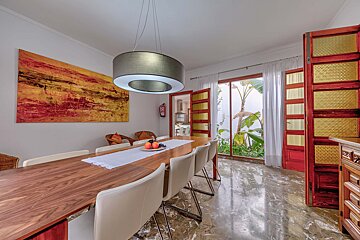 A dining room with a table and chairs and a painting on the wall