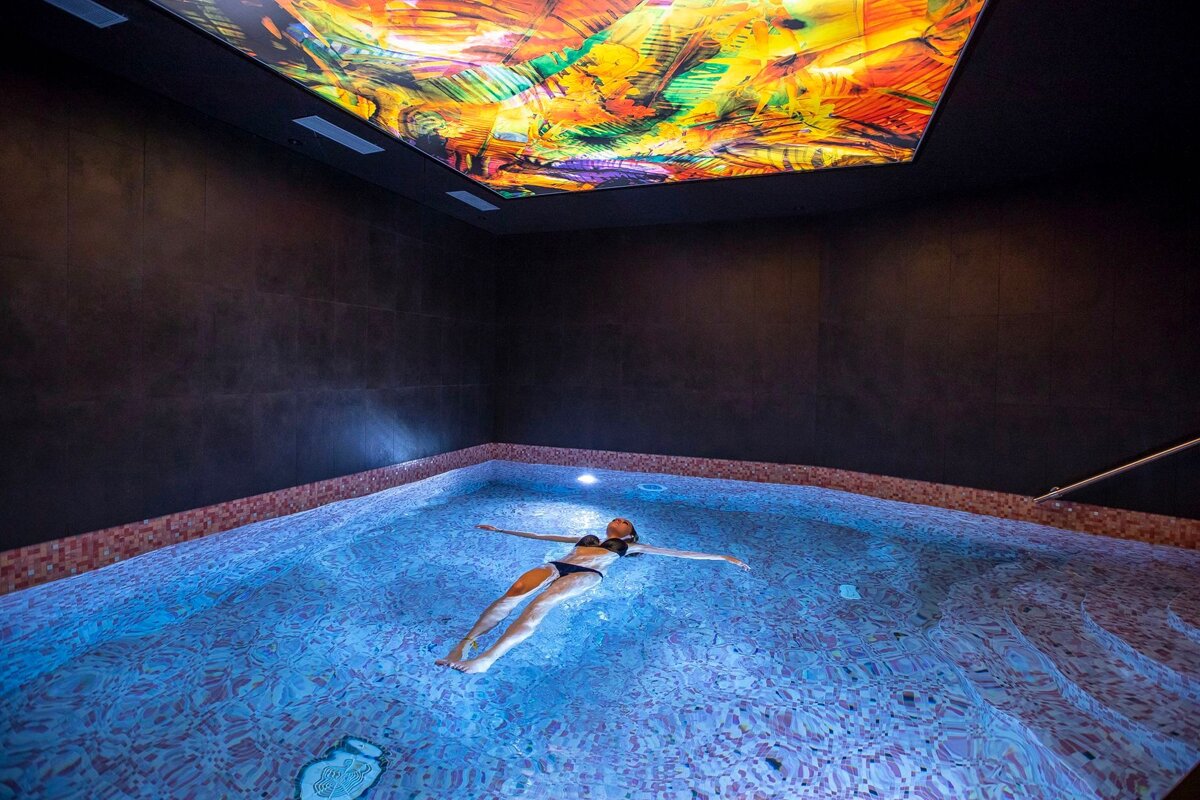 A woman is floating in a pool with a colorful ceiling