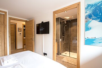 A bedroom with a television and a picture of a mountain