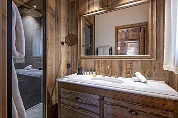 A bathroom with wooden walls and a sink and mirror