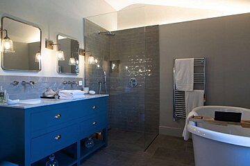 A bathroom with two sinks and a walk in shower