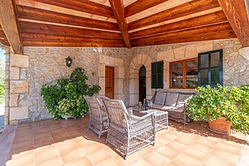 A patio with a couch and chairs under a wooden roof