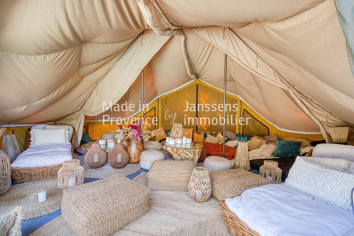 A tent with wicker furniture and a sign that says made in provence by janssens immobilier