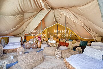 A tent with wicker furniture and a sign that says made in provence by janssens immobilier