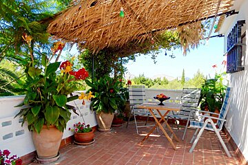 A patio with a table and chairs under a thatched roof