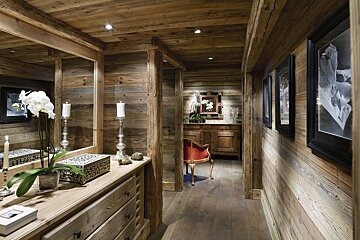 A wooden hallway with a dresser and a chair