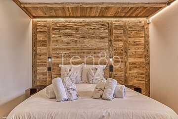 A bed in a hotel room with a wooden headboard