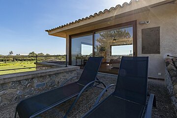 Two lounge chairs on a balcony with a sliding glass door