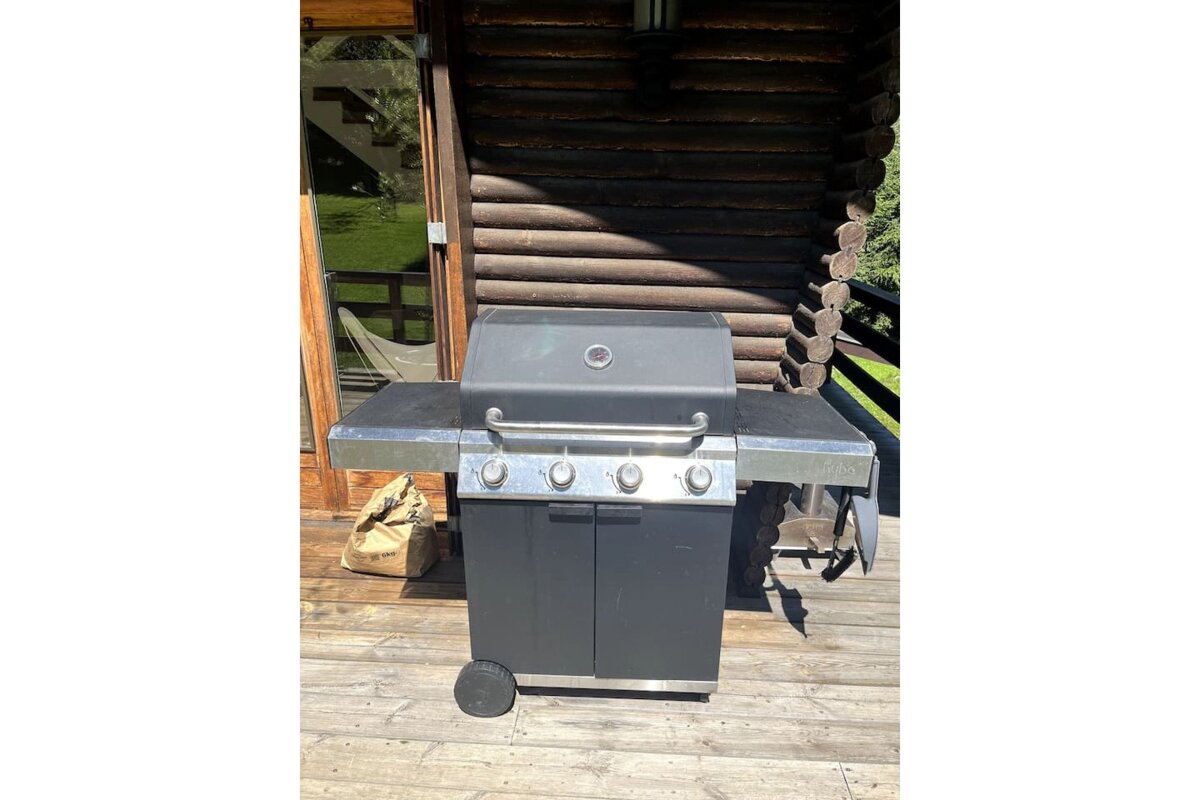 A grill is sitting on a wooden deck in front of a log cabin