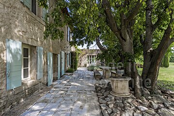 A stone building with blue shutters is for sale