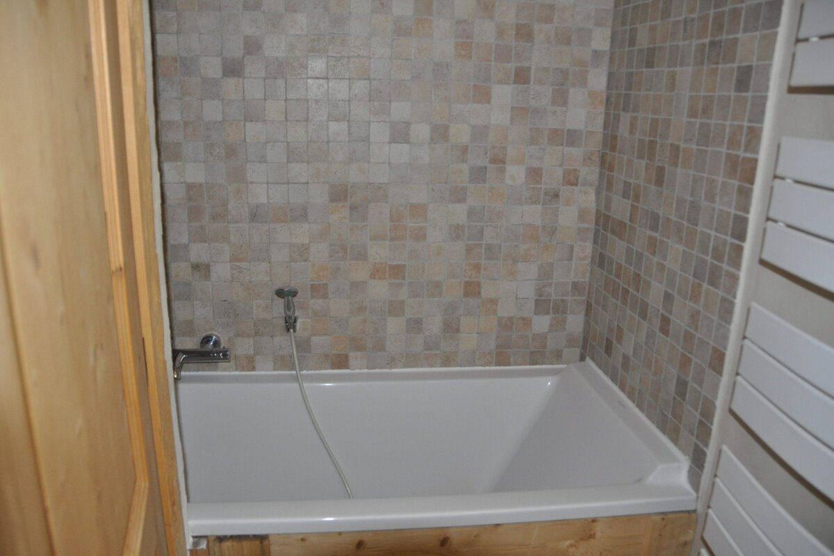 A bathtub in a bathroom with a tiled wall