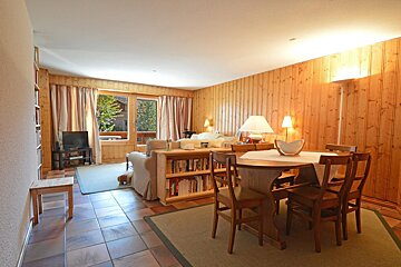 A living room with wood paneling and a table and chairs