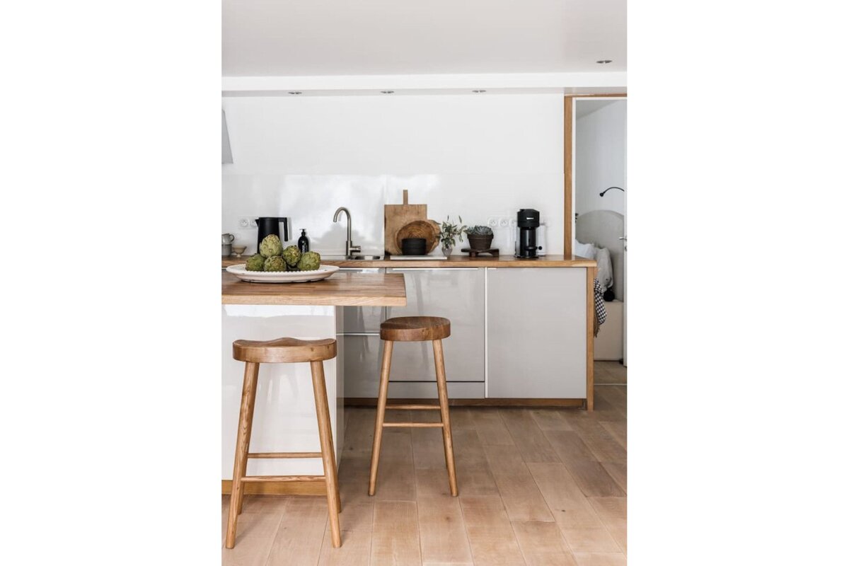 A kitchen with white cabinets and wooden stools