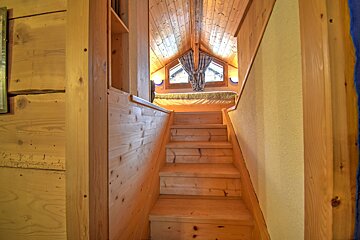 A wooden staircase leading up to a bedroom with a bed
