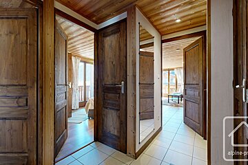 A hallway with wooden doors and a sign that says alpine-pro