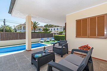 A patio with chairs and a table with a bottle of wine on it