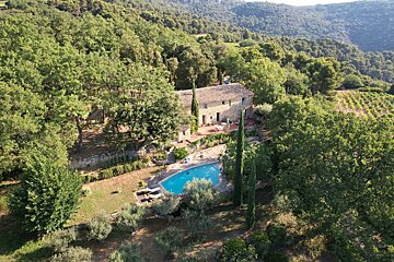 An aerial view of a house surrounded by trees and a large pool
