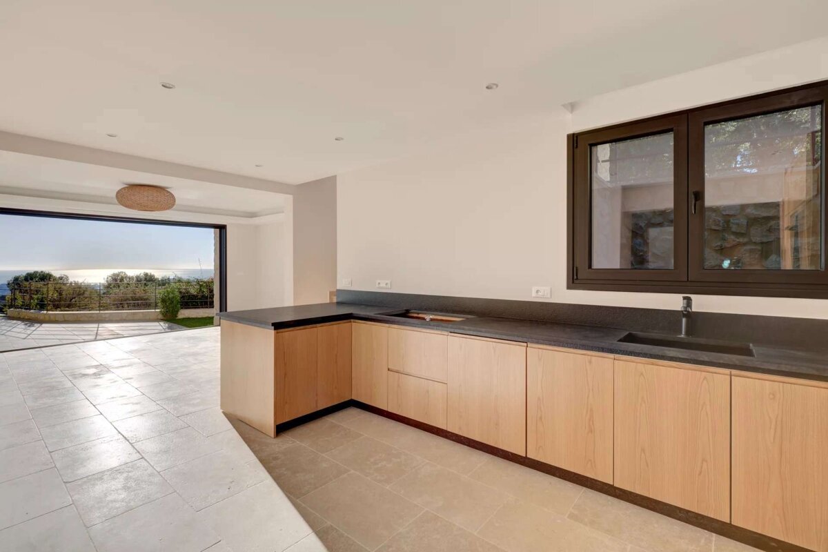 An empty kitchen with wooden cabinets and black counter tops