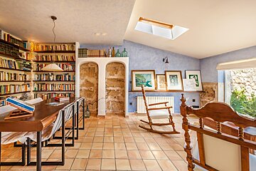 A rocking chair sits in front of a bookshelf filled with books