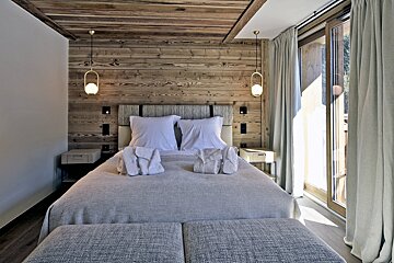 A bedroom with a wooden wall and a bed