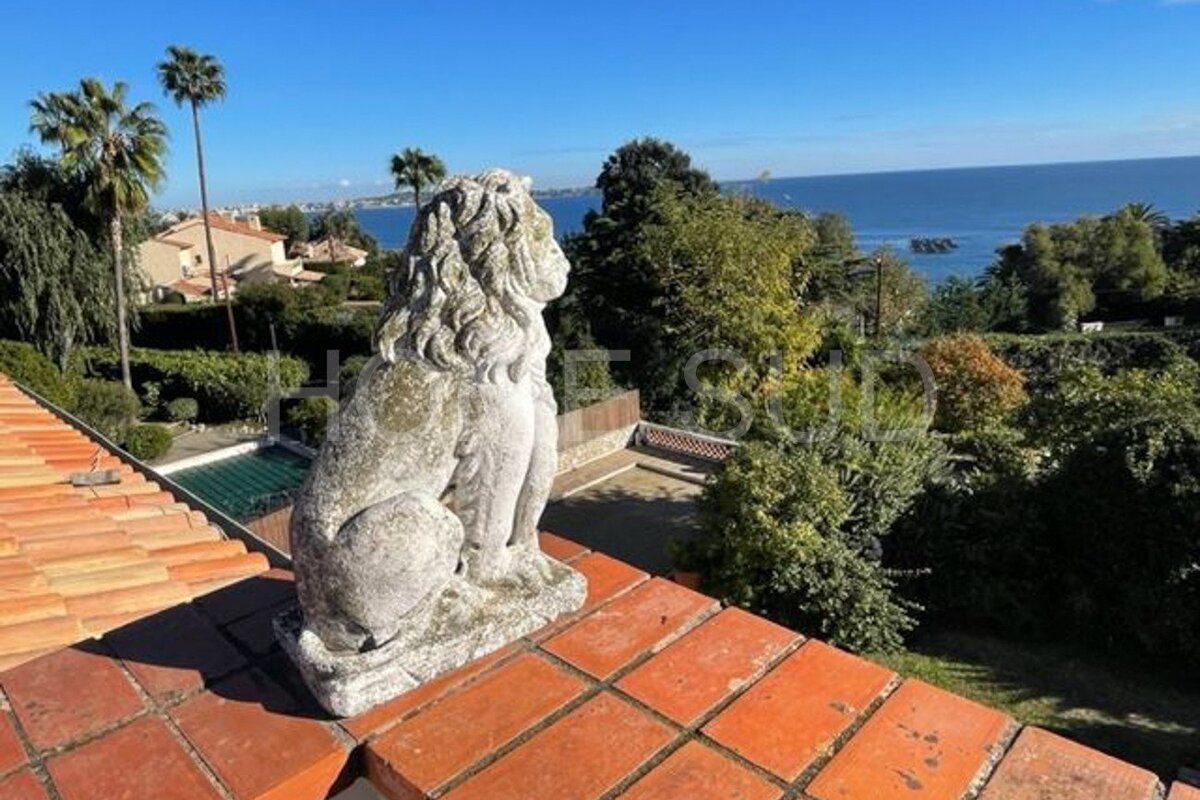 A statue of a lion sits on a roof overlooking the ocean