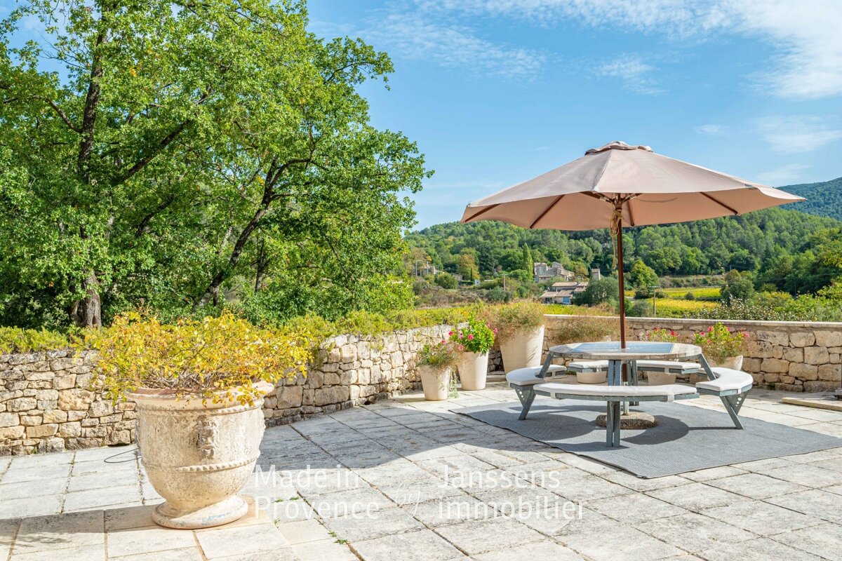 A patio with a picnic table and an umbrella that says made in provence