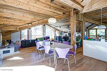 A dining room with purple chairs and a white table