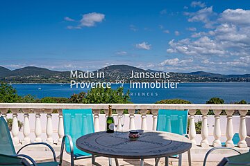 A bottle of champagne sits on a table in front of a balcony that says made in provence by immobilier