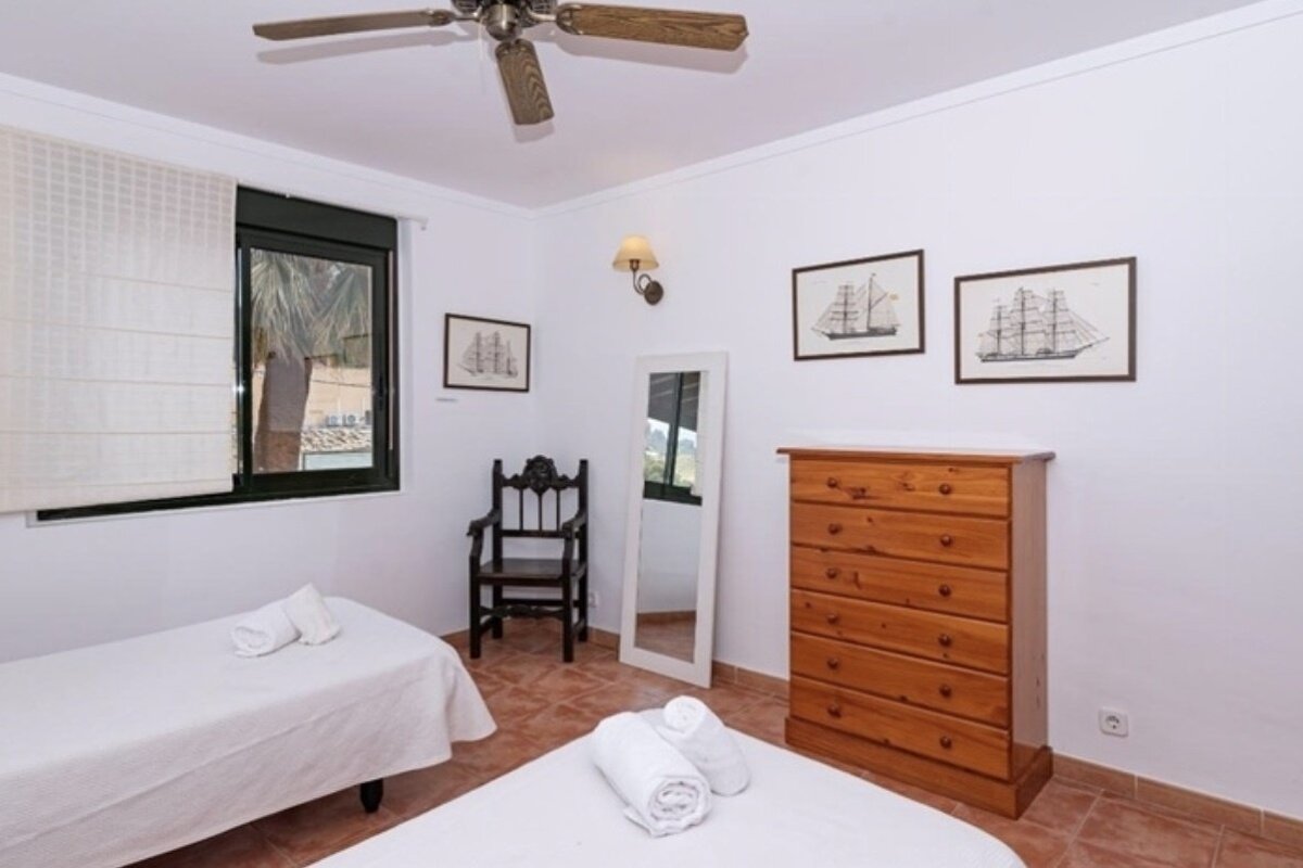 A bedroom with two beds a dresser and a chair