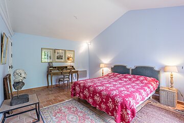 A bedroom with a large bed and a desk