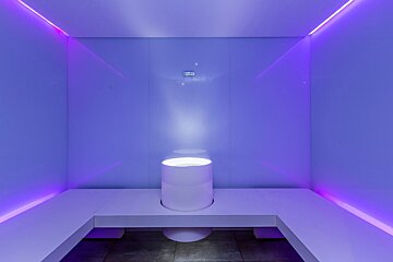 A room with purple lights and a white cylinder in the middle