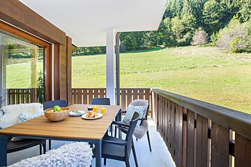 A balcony with a table and chairs and a bowl of fruit