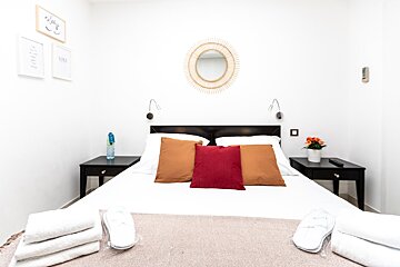 A bedroom with a bed with a red pillow on it