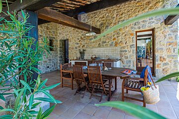 A wooden table and chairs on a stone patio