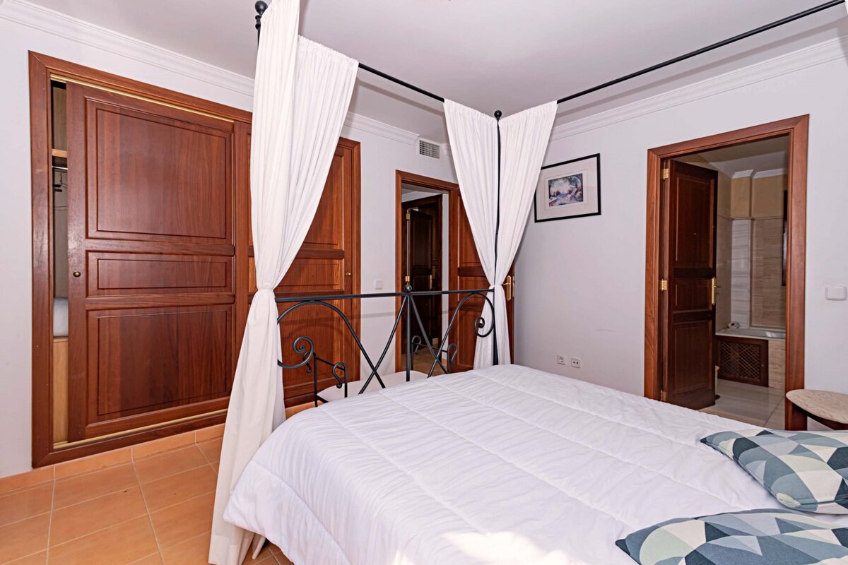 A bedroom with a canopy bed and a picture on the wall